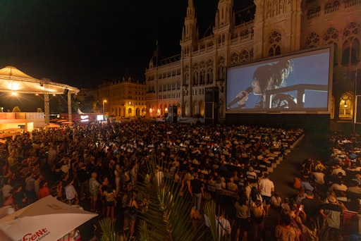 Vorschau Bild von Tausende Besucher*innen verfolgen das Konzert von Billie Eilish
auf der großen Leinwand – Kinofeeling unter freiem Himmel beim Film
Festival auf dem Wiener Rathausplatz.