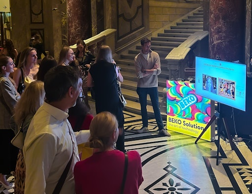 Besucher*innen interagieren mit einem Bildschirm, der von BEKO
Solutions im Rahmen des Projekts „LOOK AiLIKE“ bei dem Event
Kunstschatzi aufgestellt wurde. Der Bildschirm ermöglicht es den
Besucher*innen, ihren „Kunst-Zwilling“ zu finden. Im Bild stehen
mehrere Personen rund um den Bildschirm, während eine Person gerade
die Funktion ausprobiert.