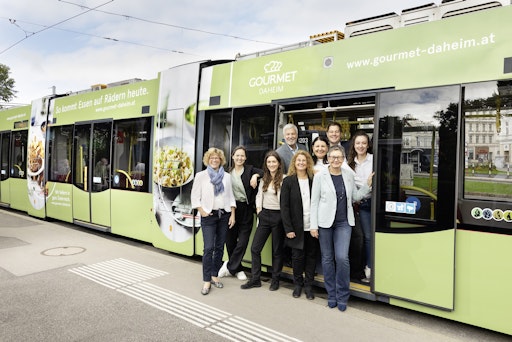 GOURMET Geschäftsführer Herbert Fuchs (hinten links),
Geschäftsfeldleitung Care Catering Mag.a Helga Cvitkovich-Steiner
(vorne rechts) und das Team von GOURMET Daheim vor der gebrandeten
Niederflur-Straßenbahn.