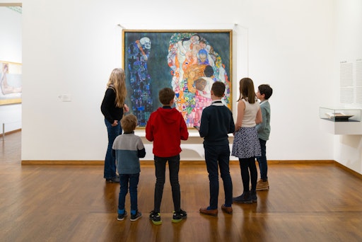 Vorschau Bild von Führungen für Kinder und Jugendliche durch die permanente
Ausstellung "Wien 1900. Aufbruch in die Moderne" im Leopold Museum,
Wien: Kinderführung –Gruppe mit Kunstvermittlerin vor dem Gemälde
"Tod und Leben" von Gustav Klimt