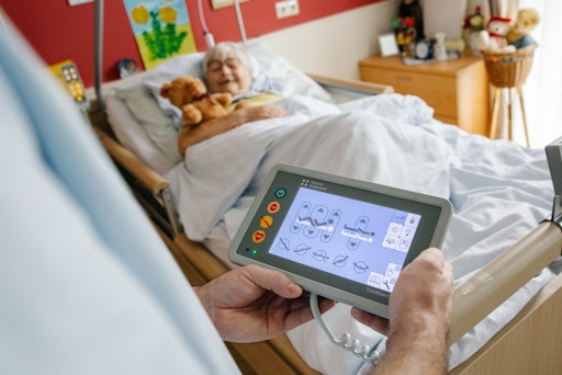 Pflegekraft bedient mittels Tablet das digitale Pflegebett.