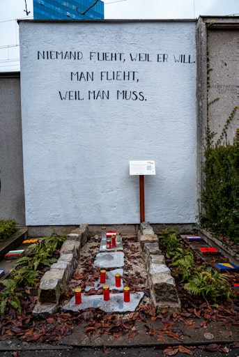 Vorschau Bild von Die Gedenkstätte erzählt in ihrer Symbolik eine eindringliche
Geschichte: Ein eingemauerter Weg steht für die verschlossenen
Grenzen Europas, an denen das Menschenrecht auf Asyl oft de facto
endet. Fußspuren, die Schritt für Schritt heller werden, erinnern an
Menschen, die auf der Flucht verschwunden sind – ausgelöscht aus
Registern, aber nicht aus der Verantwortung Europas.