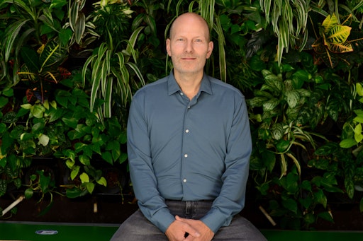 Vorschau Bild von a&o Hostels Gründer und CEO Oliver Winter sitzend vor einer
bepflanzten Wand