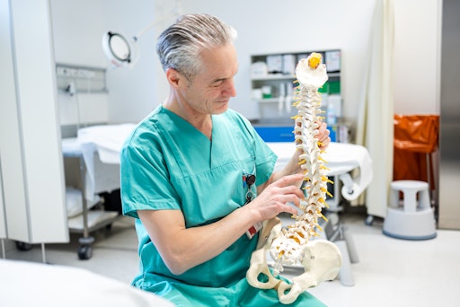 Vorschau Bild von Oberarzt Dr. Stefan Schenk mit einem Wirbelsäulenmodell