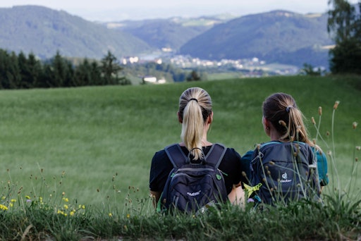 Zwei Frauen machen eine Rast auf ihrer Wanderung und blicken
sitzend ins Tal.