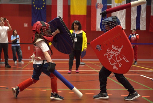  Zwei Nachwuchsathlet:innen im Bewerb Schwert & Schild während der
5. Soft Armored Fighting Europameisterschaft (01.–03. Mai 2026) in
der Sporthalle Simmering in Wien. Im Hintergrund steht die
Schiedsrichterin Flora Lelièvre (Frankreich). Insgesamt nahmen 172
Sportler:innen aus 13 europäischen Ländern in 53 Bewerben und 12
Altersklassen teil. Soft Armored Fighting ist eine besonders
inklusive Spielform des Medieval Combat-Sports, die mit gepolsterten
Waffen ausgetragen wird und sichere Wettkämpfe für Kinder,
Jugendliche und Erwachsene ermöglicht. Foto: Armored Combat Austria
(ACA)