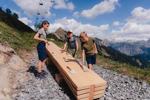 Kinder an einer Spielstation des Murmelwegs in Faschina
