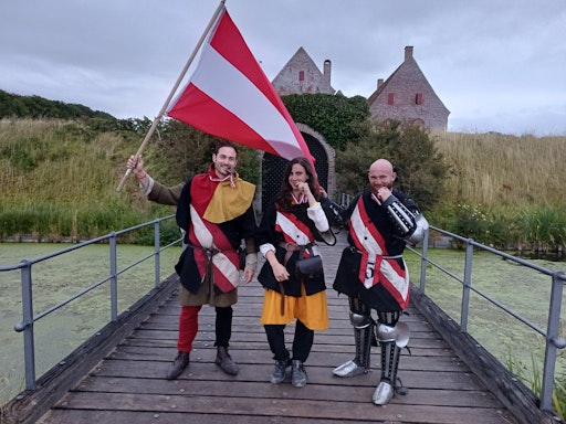 Die österreichischen Medaillengewinner:innen der Medieval
Combat-Weltmeisterschaft 2026 in Dänemark präsentieren ihre
Medaillen vor der Burg Spøttrup: Matthias GORR (VgVK Wien), Amelie
ÖHLINGER (VgVK Wien) und Maximilian HÖLLER (MCU Pyhra), von links.