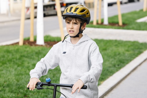 Vorschau Bild von Ein Junge steht mit seinem Roller auf einem Gehweg. Er trägt
dabei einen Schutzhelm.