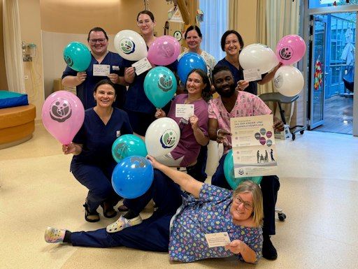 Das Team Kinderpflegedomizils Fridolina feiert den ersten
österreichweiten Tag der Kinder- und Jugendlichenpflege mit bunten
Luftballons und halten das Plakat zum Aktionstag in die Kamera.