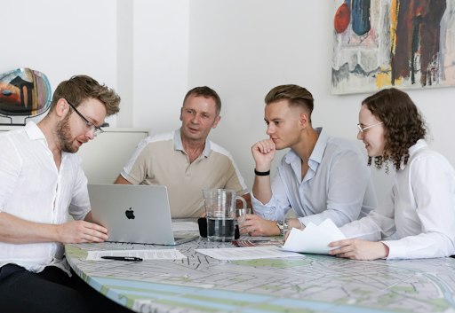 Arbeitsgespräch bei Czako Partner: Geschäftsführer Mag. Helmut
Artacker im Austausch mit seinem Team über aktuellen Unterlagen und
Plänen am Laptop.