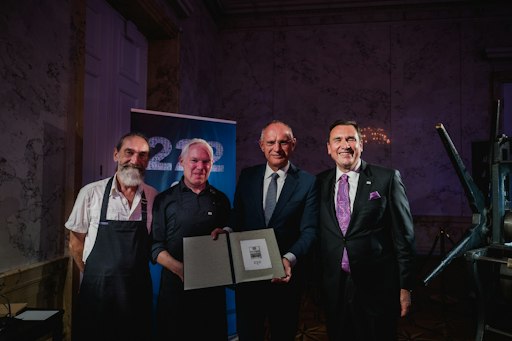 Vorschau Bild von Bundesminister Mag. Gerhard Karner mit Mag. Helmut Lackner
(Generaldirektor OeSD GmbH) gemeinsam mit Drucktechnikern bei einer
Vorführung einer historischen Sternpresse