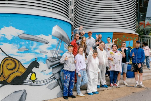Künstler*innen und Projektbeteiligte beim gemeinsamen
Street-Atelier vor den gestalteten Lüftungstürmen am Europaplatz in
Wien-Rudolfsheim-Fünfhaus. Das inklusive Kunstprojekt wurde von VOI
fesch in Kooperation mit der Gebietsbetreuung Stadterneuerung (GB)
umgesetzt.