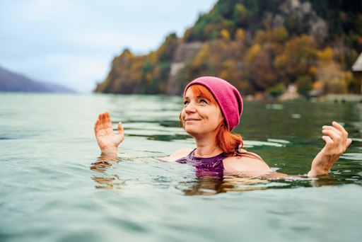 Frau mit Mütze beim Kaltbaden im See.